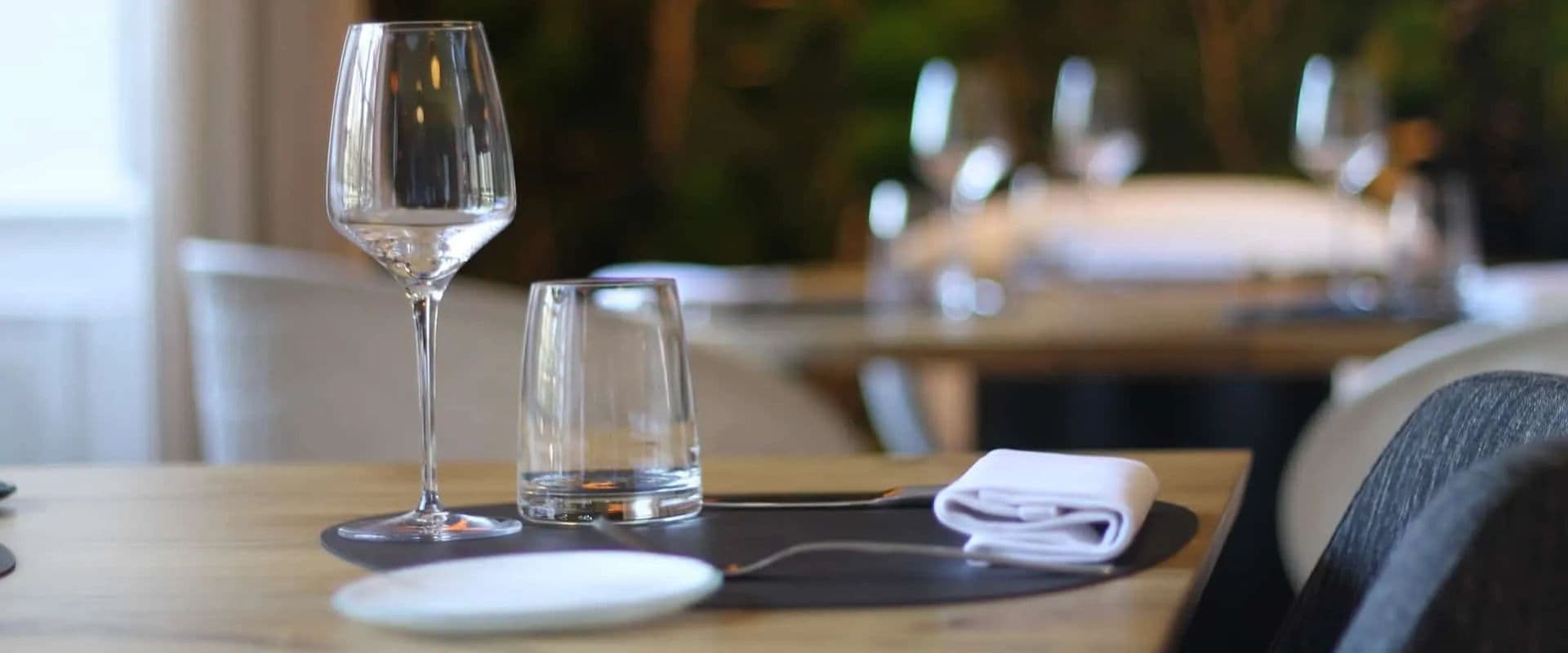A beautifully set dining table with a wine glass, water glass, napkin, and plate.
