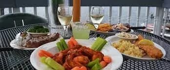 A table set with various dishes including shrimp, steak, and sides, accompanied by drinks.
